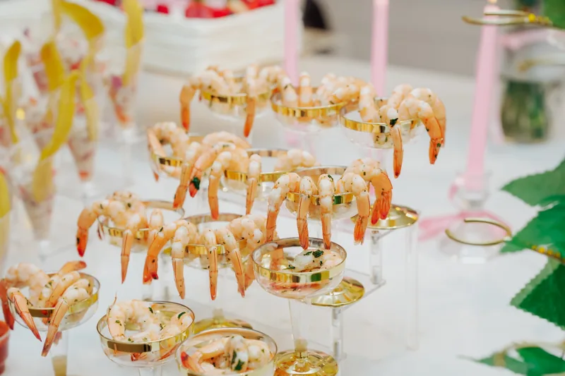 Shrimp cocktail servings in gold-rimmed glasses on a white display