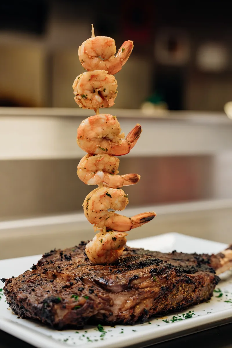 Grilled steak with a tall skewer of shrimp